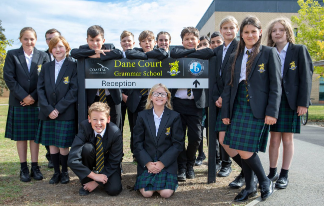 A group of students in front of the school sign